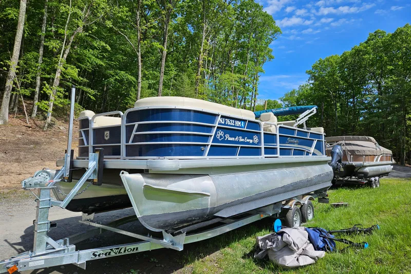 Slide: The Image of 2019 Sweetwater 2086 pontoon boat on trailer, surrounded by lush green trees. - 14