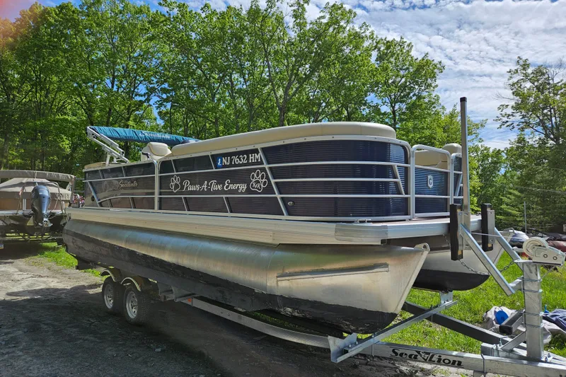 Slide: The Image of 2019 Sweetwater 2086 pontoon boat on trailer, surrounded by lush green trees. - 6