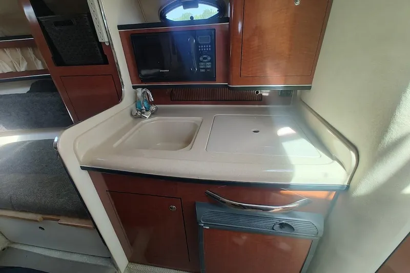 Slide: The Image of Interior of 2003 Sea Ray Sundancer 280, featuring a compact kitchenette with sink and microwave. - 15