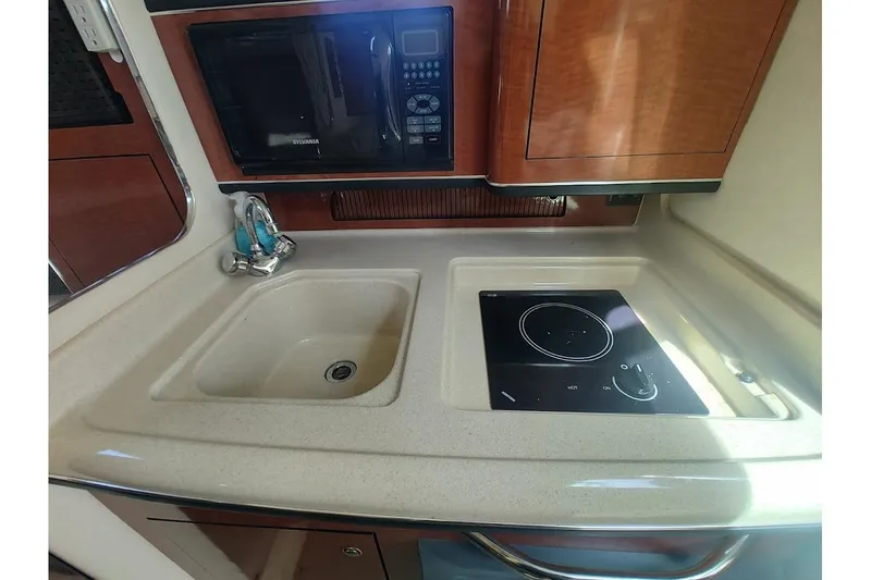 Slide: The Image of 2003 Sea Ray Sundancer 280 kitchen with sink, stovetop, and microwave. - 23