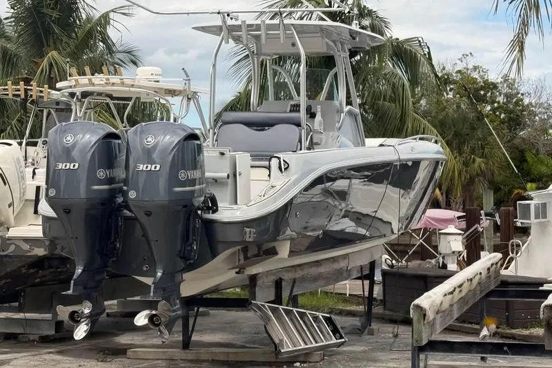 Slide: The Image of 2004 Baja 340 Sportfish boat with twin Yamaha 300 engines, docked near palm trees. - 2