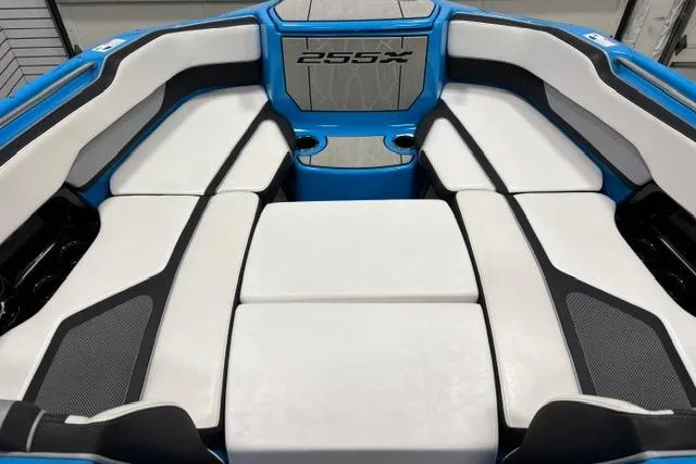 Slide: The Image of 2023 Yamaha Boats 255XE interior with white and black seating, blue accents, and cup holders. - 11