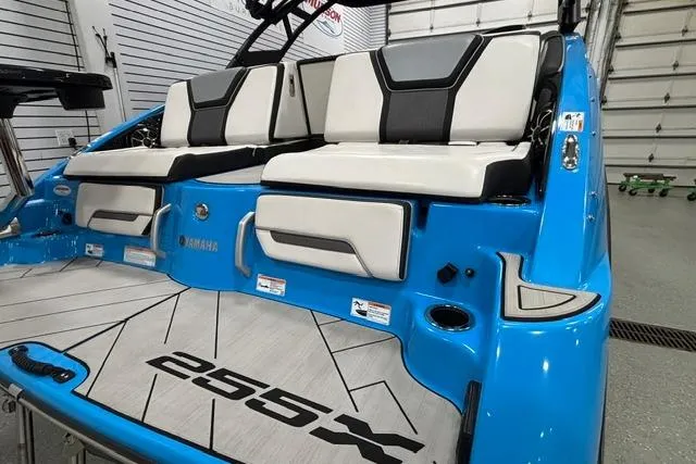 Slide: The Image of 2023 Yamaha Boats 255XE, blue exterior, luxury seating, modern design, in a showroom setting. - 15