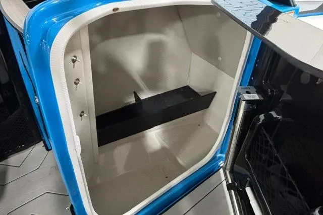 Slide: The Image of 2023 Yamaha Boats 255XE storage compartment with blue trim and interior shelving. - 29