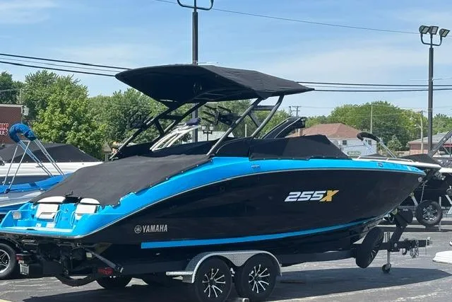 Slide: The Image of 2023 Yamaha Boats 255XE in black and blue on a trailer, parked outdoors. - 3