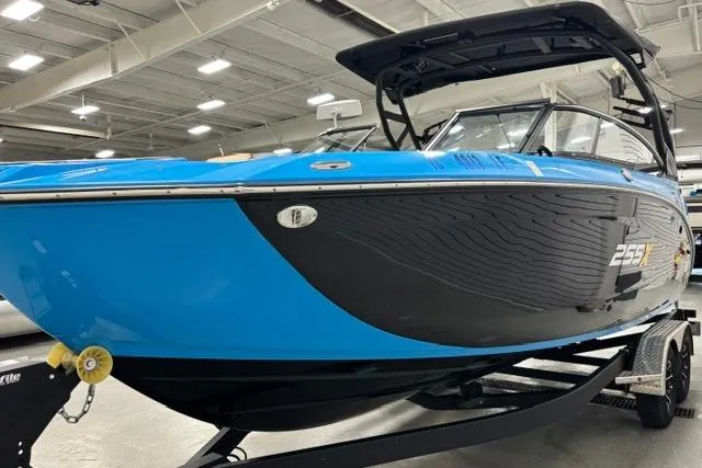 Slide: The Image of 2023 Yamaha Boats 255XE in blue and black, displayed indoors on a trailer. - 34