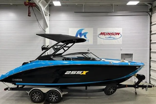 Slide: The Image of 2023 Yamaha Boats 255XE in showroom, sleek black and blue design on trailer. - 38