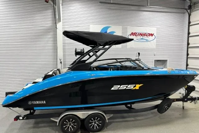 Slide: The Image of 2023 Yamaha Boats 255XE in showroom, featuring sleek black and blue design on trailer. - 39