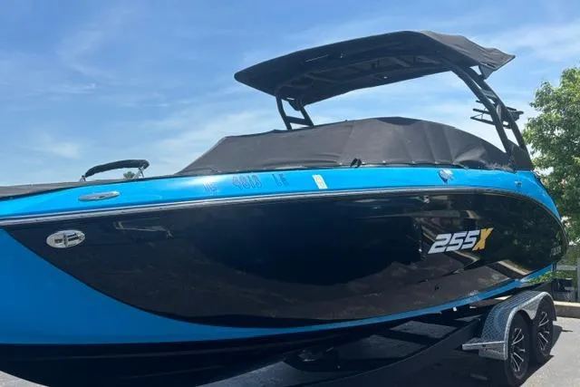 Slide: The Image of 2023 Yamaha Boats 255XE, sleek blue and black design, parked on a trailer. - 4