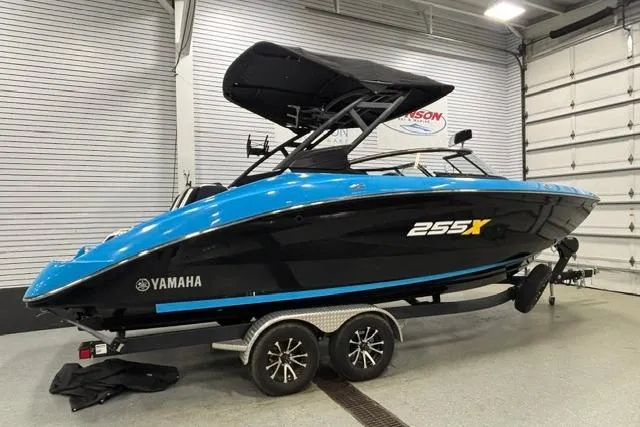 Slide: The Image of 2023 Yamaha Boats 255XE in showroom, sleek black and blue design on trailer. - 40