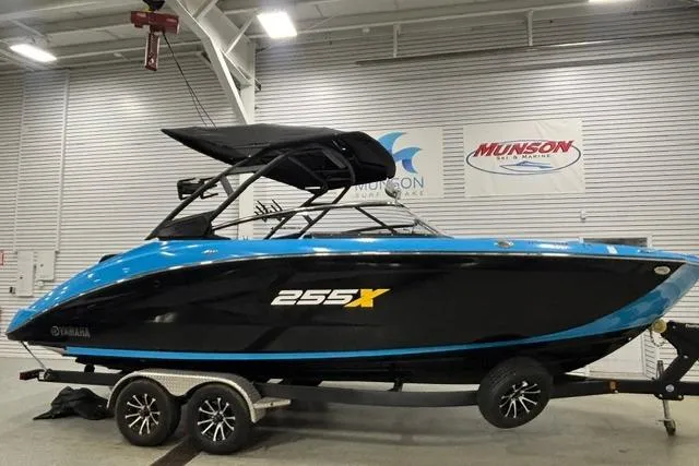 Slide: The Image of 2023 Yamaha Boats 255XE in showroom, sleek black and blue design on trailer. - 41