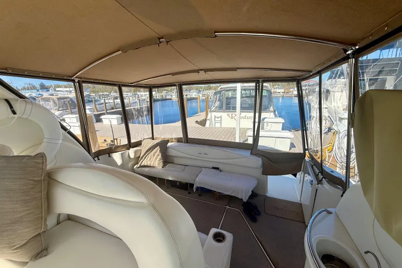 Slide: The Image of Interior view of a 2000 Sea Ray 410 Express Cruiser, featuring comfortable seating and marina backdrop. - 7