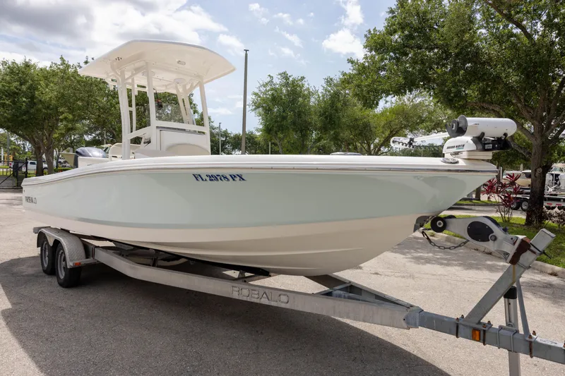 The Image of 2015 Robalo 246 Cayman boat on trailer, parked outdoors under a cloudy sky. - 1