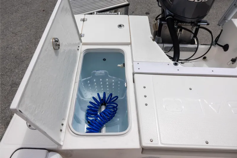 Slide: The Image of Open storage compartment on 2015 Robalo 246 Cayman boat with coiled blue hose. - 10