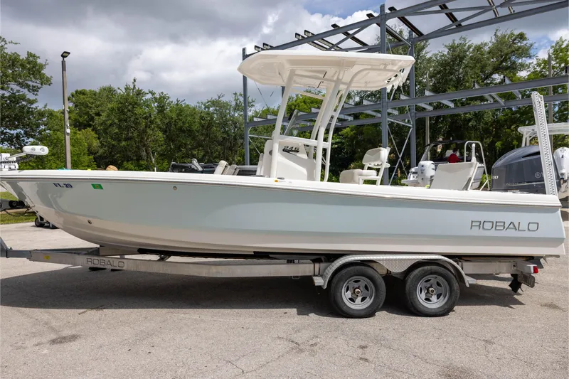 Slide: The Image of 2015 Robalo 246 Cayman boat on trailer, parked outdoors under cloudy sky. - 5