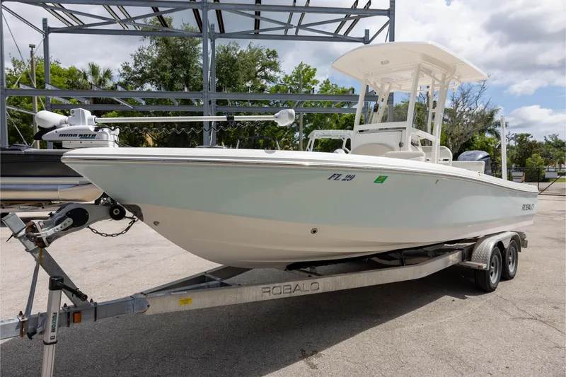 Slide: The Image of 2015 Robalo 246 Cayman boat on trailer, parked outdoors under a cloudy sky. - 6