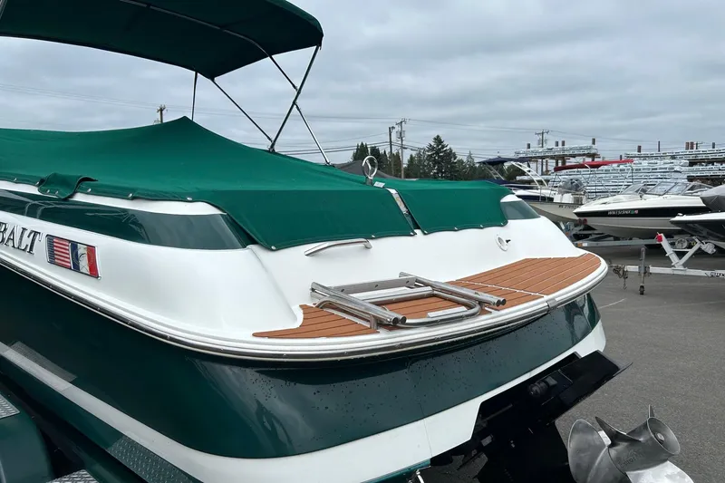 Slide: The Image of 1995 Cobalt 253 boat with green cover and swim platform, parked in marina. - 2
