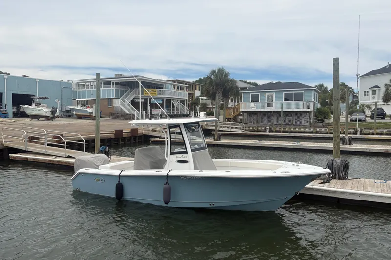 The Image of 2025 Sea Hunt Gamefish 25 boat docked at a marina with waterfront homes. - 1