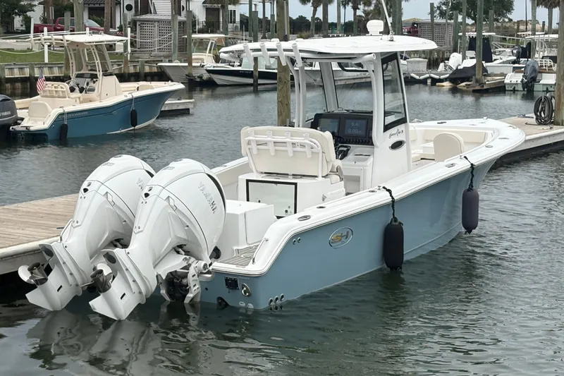 Slide: The Image of 2025 Sea Hunt Gamefish 25 boat docked with dual outboard engines in a marina. - 10