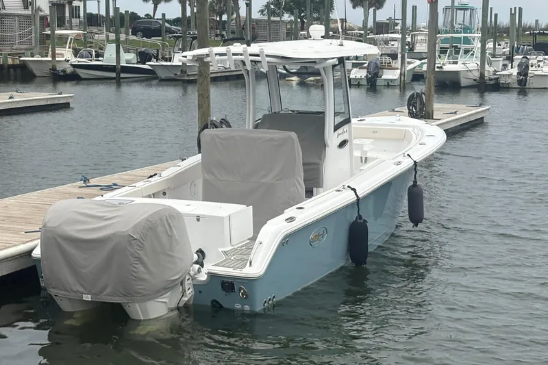 Slide: The Image of 2025 Sea Hunt Gamefish 25 boat docked in marina, covered engines, calm water. - 4
