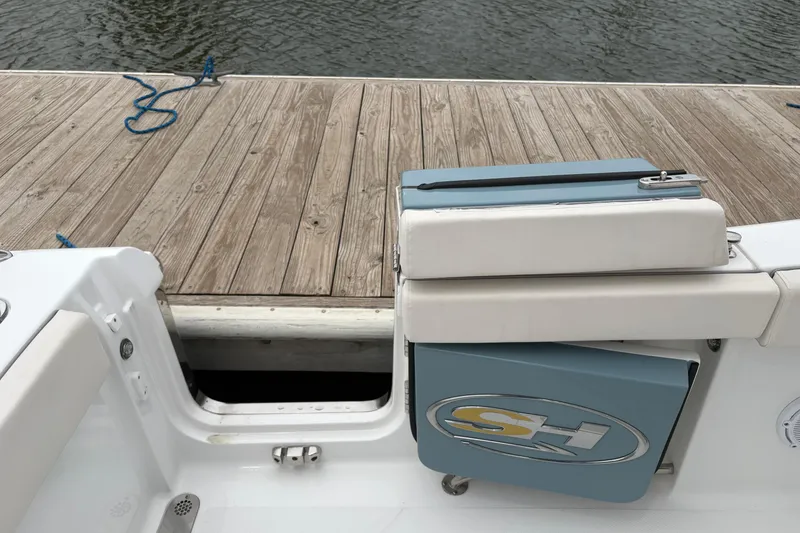 Slide: The Image of 2025 Sea Hunt Gamefish 25 boat at dock, featuring cushioned seating and storage compartment. - 41