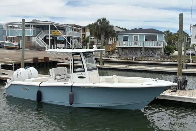 Slide: The Image of 2025 Sea Hunt Gamefish 25 boat docked at a marina with coastal homes in the background. - 8