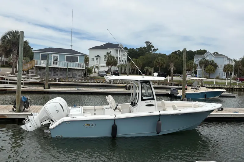 Slide: The Image of 2025 Sea Hunt Gamefish 25 boat docked at a marina with waterfront homes. - 9