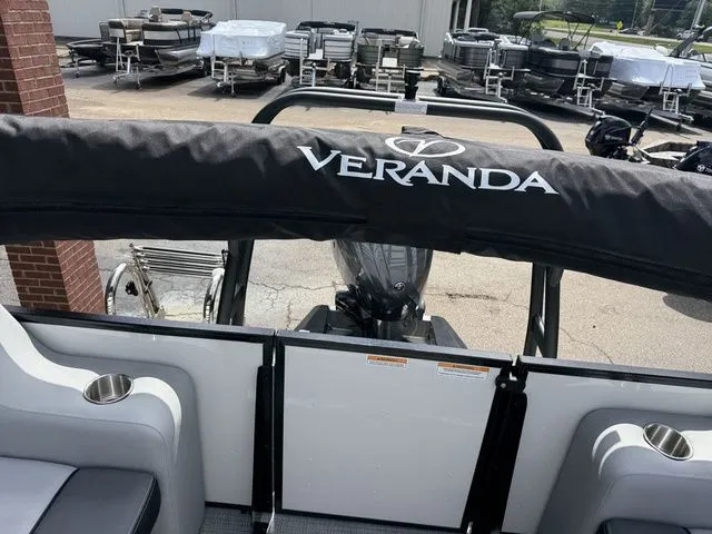 Slide: The Image of Veranda VV 22RC 2026 pontoon boat with cover, parked outdoors. - 21