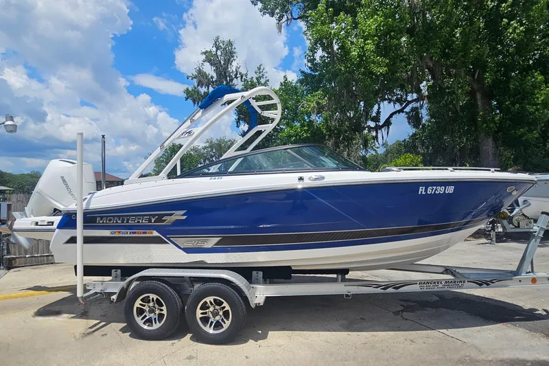 Slide: The Image of 2024 Monterey 215SS Super Sport boat on trailer, blue and white design, parked outdoors. - 4