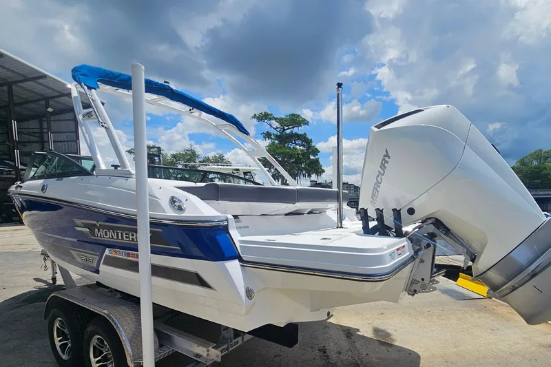 Slide: The Image of 2024 Monterey 215SS Super Sport boat with Mercury engine, parked outdoors under a cloudy sky. - 6
