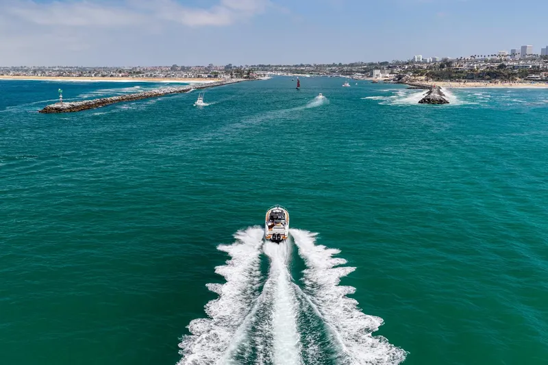 Slide: The Image of 2023 Fairline F//Line 33 Outboard cruising in vibrant blue waters near a coastal city. - 15