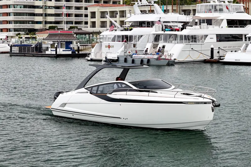 Slide: The Image of 2023 Fairline F//Line 33 Outboard cruising in a marina, surrounded by luxury yachts. - 22