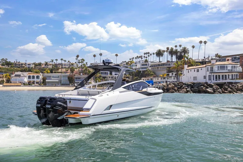 Slide: The Image of 2023 Fairline F//Line 33 Outboard cruising near coastal homes under a sunny sky. - 5