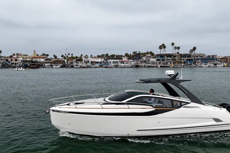 Slide: The Image of 2023 Fairline F//Line 33 Outboard cruising near a coastal town under cloudy skies. - 67