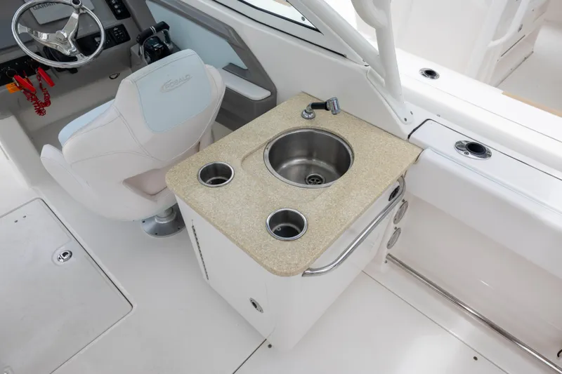 Slide: The Image of 2018 Robalo R247 Dual Console boat interior with helm, sink, and cup holders. - 5