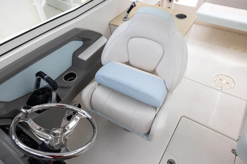 Slide: The Image of 2018 Robalo R247 Dual Console helm with steering wheel and cushioned seat. - 8