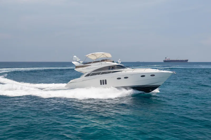 Slide: The Image of 2009 Princess 54 Flybridge yacht cruising on open sea with distant ship in background. - 4