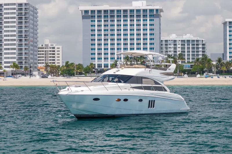 Slide: The Image of 2009 Princess 54 Flybridge yacht cruising near a beach with tall buildings in the background. - 22