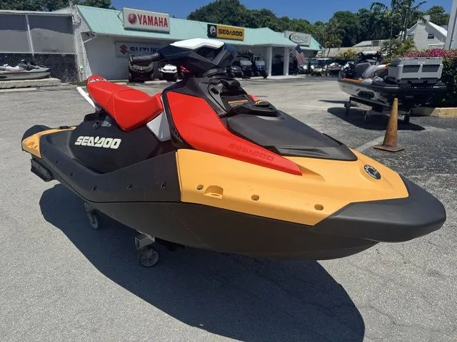 Slide: The Image of 2025 Sea-Doo Spark for 3, red and yellow, outdoors at a dealership. - 3