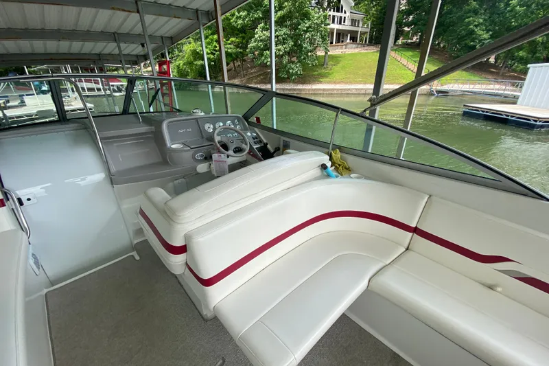 Slide: The Image of 2001 Formula 330 Sun Sport boat interior with white seating and red accents, docked by a lake. - 42