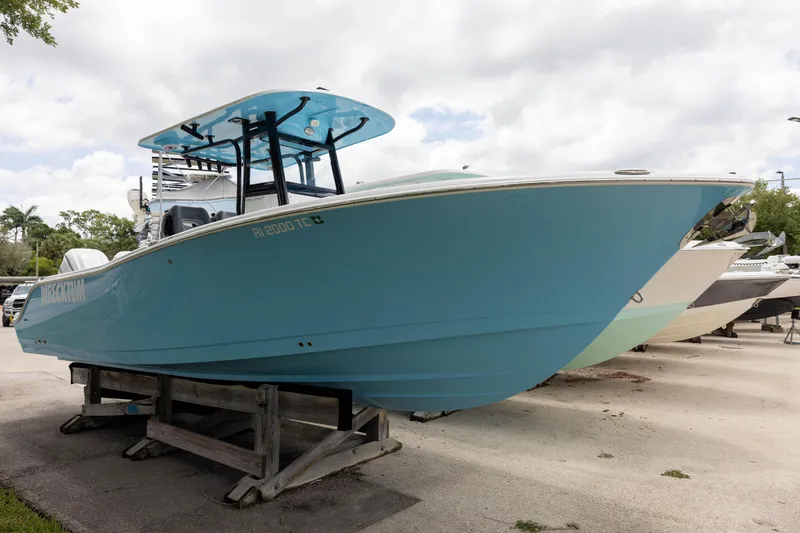 The Image of 2024 NauticStar 292 Legacy boat in vibrant blue, displayed on a wooden stand outdoors. - 0