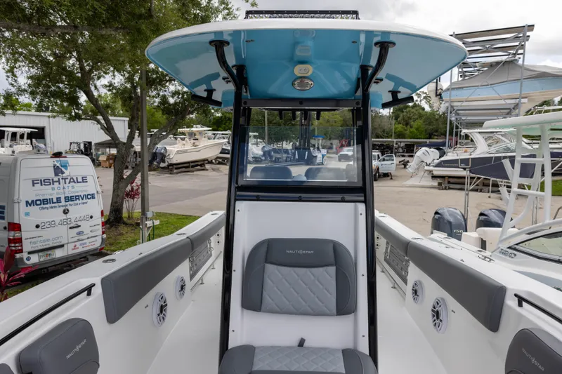 Slide: The Image of 2024 NauticStar 292 Legacy boat interior with seating and console, in a marina setting. - 18