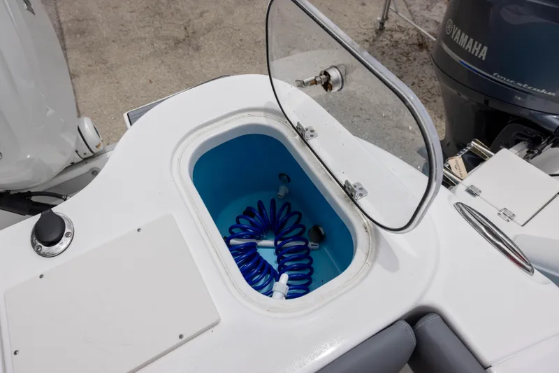 Slide: The Image of 2024 NauticStar 292 Legacy boat with open storage compartment and coiled blue hose. - 9