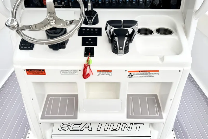 Slide: The Image of 2023 Sea Hunt Escape 28 helm with steering wheel, controls, and cup holders. - 14