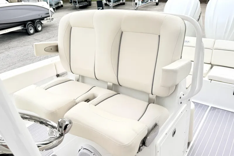 Slide: The Image of 2023 Sea Hunt Escape 28 boat with plush white seating and steering wheel. - 16