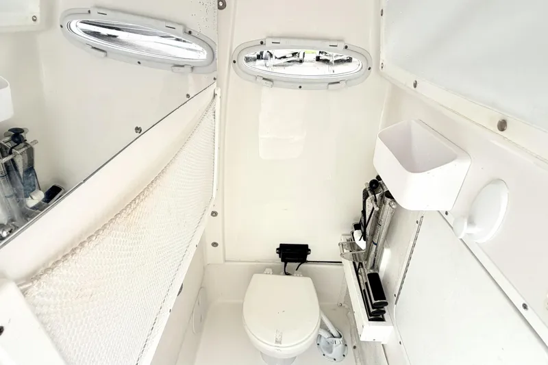 Slide: The Image of Interior of 2023 Sea Hunt Escape 28 boat bathroom with toilet and storage. - 23
