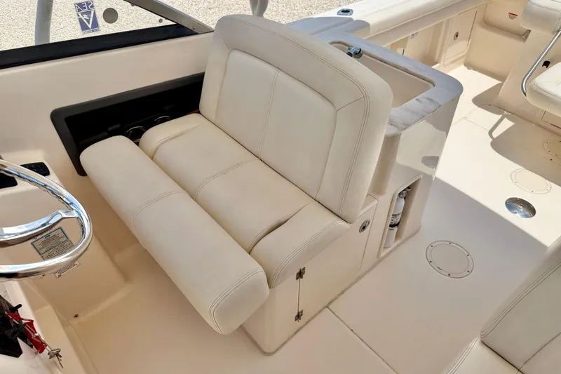 Slide: The Image of 2015 Grady-White Freedom 275 boat interior with white seating and steering wheel. - 22
