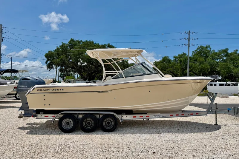Slide: The Image of 2015 Grady-White Freedom 275 boat on trailer, parked outdoors under clear blue sky. - 4