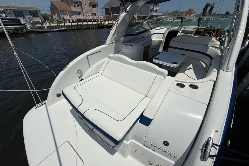 Slide: The Image of 2012 Formula 350 Sun Sport boat interior with white seating and table, docked by waterfront homes. - 7