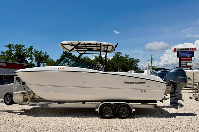 The Image of 2021 Twin Vee 240 GFX DC boat on trailer, parked outdoors under clear sky. - 0